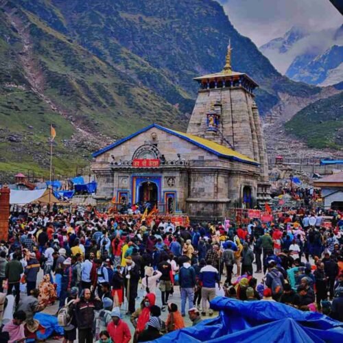 Pilgrims gathered at Kedarnath Temple, with the Himalayas rising in the background beneath cloudy skies.