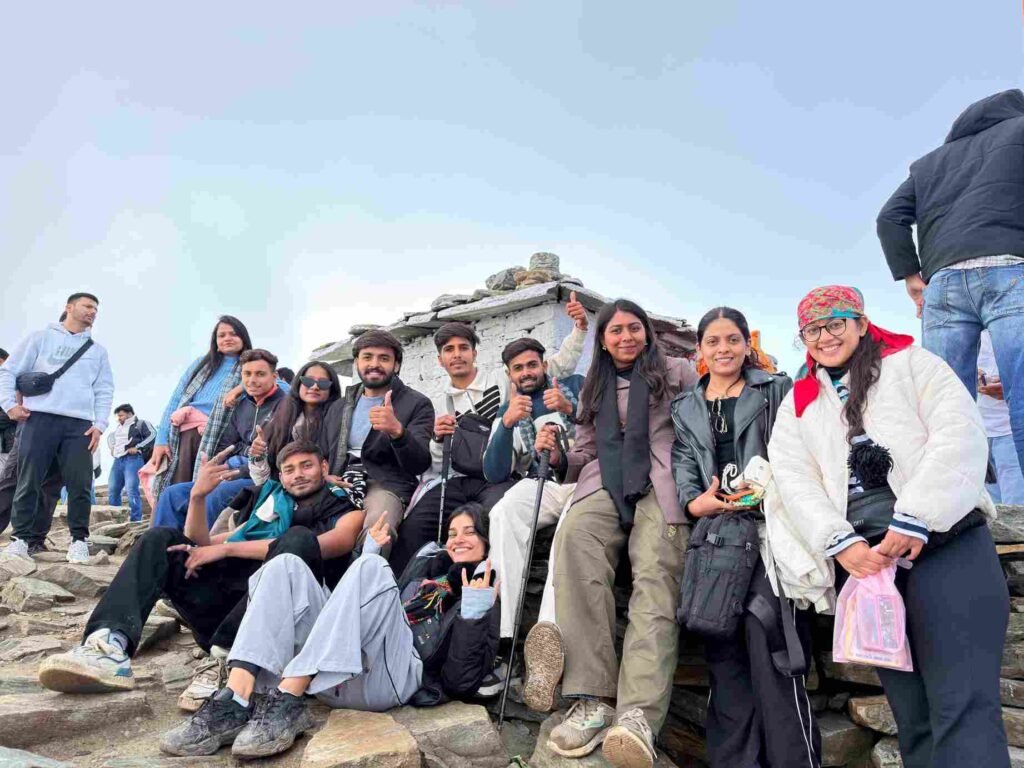 A group of friends posing together on a rocky mountain summit, smiling and celebrating after a trek.