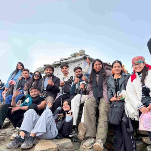 A group of friends posing together on a rocky mountain summit, smiling and celebrating after a trek.
