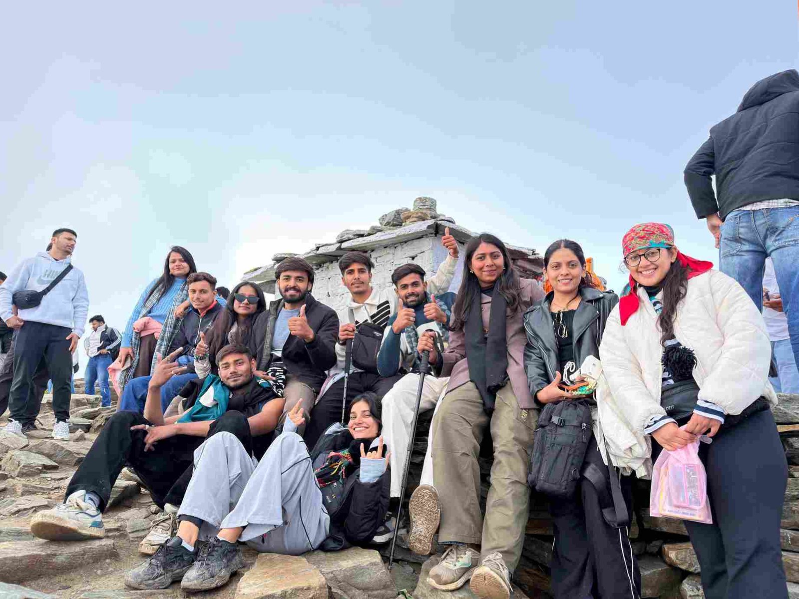 A group of friends posing together on a rocky mountain summit, smiling and celebrating after a trek. 